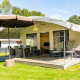 Safari-telt med terrasse og parasol ved De Witte Berg feriepark i Holland, omgivet af grøn natur.