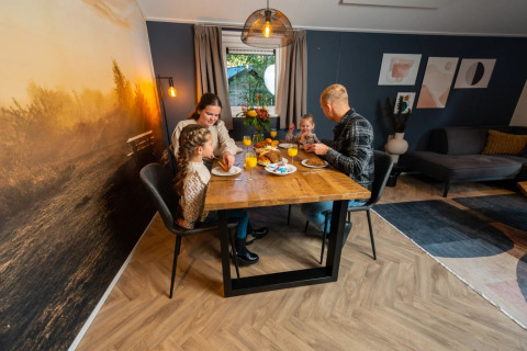 Gezin geniet samen van een maaltijd in een gezellige glamping accommodatie op een vakantiepark.