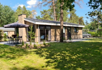 Moderne lodge met grote tuin, eethoek buiten en omgeven door hoge groene bomen en natuur.