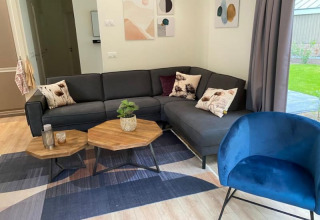 Sala de estar de lodge moderna con sofá gris en L, sillón azul, mesas hexagonales y arte en las paredes.