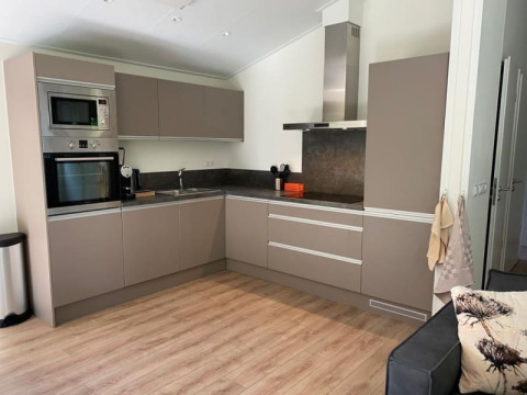 Petite cuisine moderne en lodge avec sol en bois, placards gris et appareils encastrés en coin.