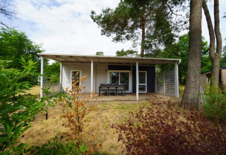 Logement de glamping charmant dans une cabane moderne, entourée de nature, d’arbres et d’un coin repas.