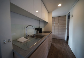 Moderne glamping-keuken met gootsteen, houten kasten en houten vloer, langs het aanrecht gezien.