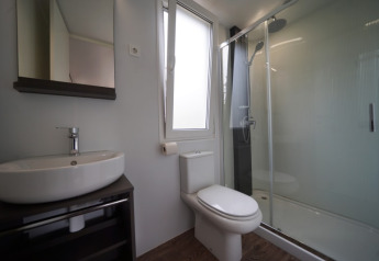 Moderne badkamer in een glamping-accommodatie met douche, toilet, wastafel en wandspiegel.