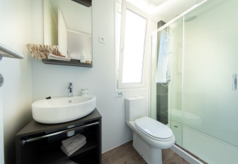 Moderne badeværelse på et lodge med vask, spejlskab, toilet, stort vindue og bruseniche med glasdør.
