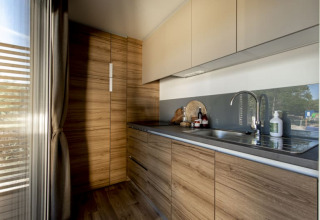 Moderne Lodgeküche mit Holzschränken, grauer Arbeitsplatte und großem Fenster mit Tageslicht.