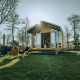 Wikkelhouse Bear naturhus ved De Klepperstee feriepark i Holland, omgivet af grønne træer og sollys.