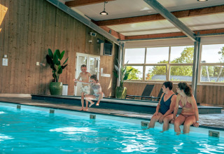 Gezellige sfeer in het binnenzwembad van een vakantiepark met glamping, waar gezinnen samen ontspannen.
