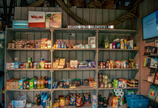 Winkelrekken in een vakantiepark met diverse snacks, drankjes en huishoudproducten, ideaal voor kampeerders.