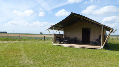 Safari-Zelt mit Terrasse und Sitzgelegenheiten auf dem Minicamping de Vrolijke Flierefluiter in den Niederlanden.