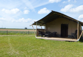 Safari-telt med veranda og siddepladser på Minicamping de Vrolijke Flierefluiter i Holland; udsigt til marker.