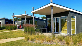 Casa pequeña moderna Comfort Lodge en Kompas Camping Nieuwpoort en Bélgica, en un día soleado con cielo azul.