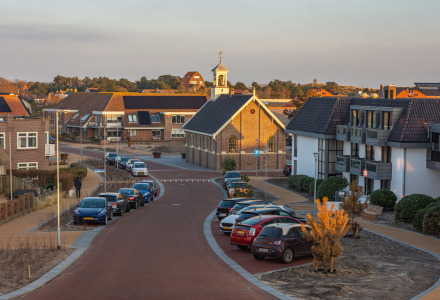 Foto de una tranquila zona residencial cerca de Breezand, Holanda Septentrional, con coches y una iglesia.