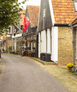 Encantadora calle de pueblo con cafeterías y casas antiguas en un parque vacacional de glamping.