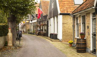 Encantadora calle de pueblo con cafeterías y casas antiguas en un parque vacacional de glamping.