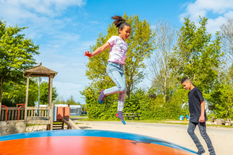 Kinderen genieten van een zonnige dag en spelen op een springkussen in een vakantiepark met glamping.