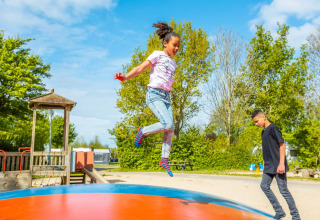 Kinderen genieten van een zonnige dag en spelen op een springkussen in een vakantiepark met glamping.