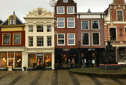 Foto de edificios históricos holandeses con tiendas en la planta baja en una calle adoquinada y turística.
