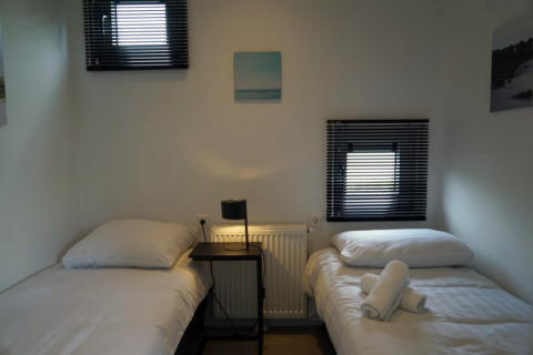 Ein einfaches Schlafzimmer mit zwei Einzelbetten, einem kleinen Tisch und Lampe in einer Lodge.