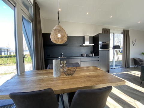 Moderne Lodge mit großem Holztisch, offener Küche und großen Fenstern mit Blick auf die Natur.
