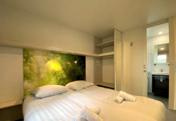 Bedroom in a glamping accommodation with double bed, open closet, nature wall art, and bathroom access.