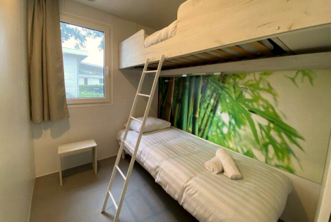 Lichte glampingkamer met stapelbed, raam, natuurbehang en minimalistisch meubilair voor een comfortabel verblijf.