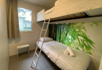Bright glamping room featuring a bunk bed, window, nature-themed wallpaper, and minimalist furnishings.
