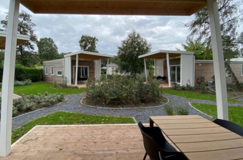 Photo d’hébergements glamping modernes avec terrasses en bois, jardins, sentiers et beaucoup de verdure.