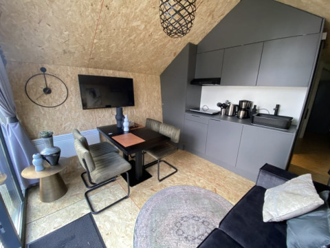 Moderne lodge med åbent køkken, spisebord, TV på væggen, stilfulde stole og dekorative detaljer.