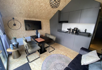 Modern lodge-interieur met strakke keuken, eetruimte, wand-tv, designstoelen en stijlvolle accenten.