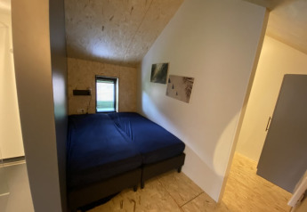 Kleine lodgekamer met twee aaneengeschoven eenpersoonsbedden, blauw beddengoed en eenvoudige decoratie.