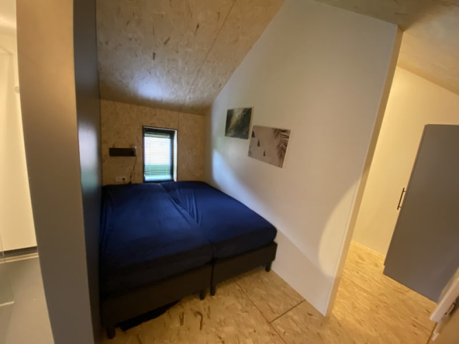 Kleines Zimmer in einer Lodge mit zwei nebeneinander gestellten Einzelbetten, blauer Bettwäsche und dekorativer Kunst.