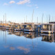 Moderne husbåde ved Marina Parcs Naarden, Holland, spejler sig i det klare vand under blå himmel.