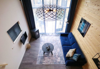 Hébergement glamping moderne avec canapé bleu, table ronde et grandes fenêtres, vue du dessus.