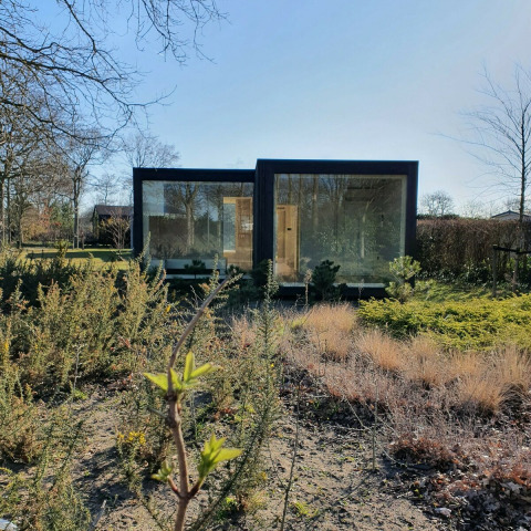 Ark Shelter natuurhuis in park De Klepperstee, Nederland, omgeven door natuur en struiken.