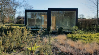 Ark Shelter natuurhuisje op vakantiepark De Klepperstee in Nederland, omringd door planten en gras.