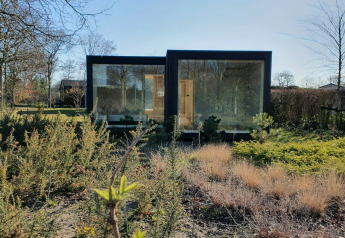Ark Shelter natuurhuisje op vakantiepark De Klepperstee in Nederland, omringd door planten en gras.