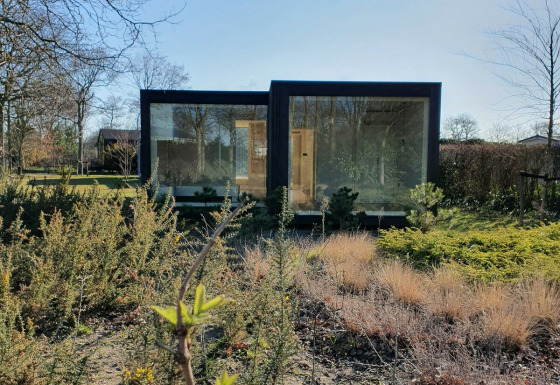 Ark Shelter natuurhuis in park De Klepperstee, Nederland, omgeven door natuur en struiken.
