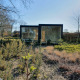 Ark Shelter i naturen ved ferieparken De Klepperstee i Holland, omgivet af træer og græs.