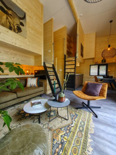Interno di tiny house elegante con pareti in legno, arredi moderni e atmosfera accogliente.