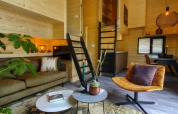 Interno di tiny house elegante con pareti in legno, arredi moderni e atmosfera accogliente.