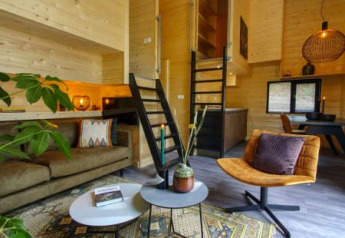 Interno di tiny house elegante con pareti in legno, arredi moderni e atmosfera accogliente.