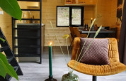 Moderne, hyggeligt tiny house interiør med trævægge, sort stige, gul lænestol og dekorativt bord.
