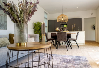 Stilfuldt åbent opholdsrum i et lodge med moderne møbler, spisebord og indbydende belysning.