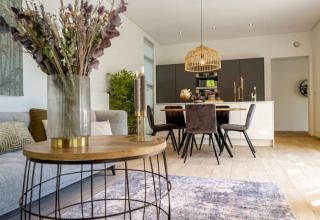 Acogedora sala-comedor de cabaña con muebles modernos, mesa de comedor y lámpara decorativa.