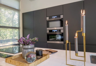 Cuisine moderne de lodge avec armoires sombres, grande fenêtre, plateau décoratif et bougies allumées.