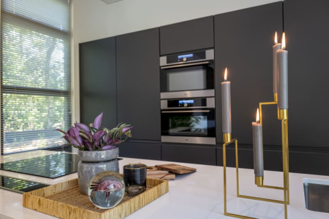 Cuisine moderne de lodge avec armoires sombres, grande fenêtre, plateau décoratif et bougies allumées.