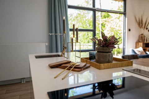 Cocina moderna de una cabaña con decoración contemporánea, plantas, velas y amplias ventanas luminosas.