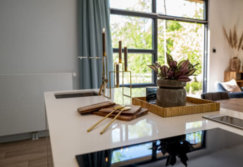 Cocina moderna de una cabaña con decoración contemporánea, plantas, velas y amplias ventanas luminosas.