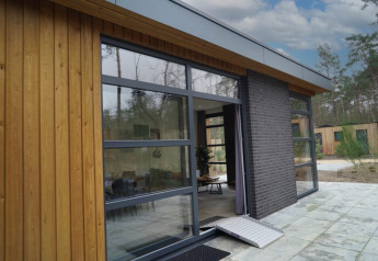 Foto esterna di un lodge moderno con grandi finestre, rivestimento in legno e rampa di accesso.